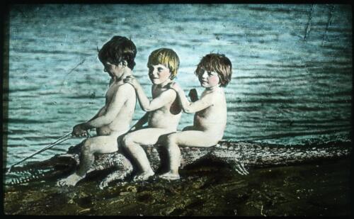 Three children on a crocodile [transparency] : taken on a survey trip undertaken in 1927 by Rev. J.A. Barber and Dr. George Simpson for the Flying Doctor Scheme