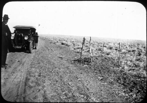Unidentified man standing next to Dodge looking at the grave of Bandy? Brady in the outback [transparency] : taken on a survey trip undertaken in 1927 by Rev. J.A. Barber and Dr. George Simpson for the Flying Doctor Scheme