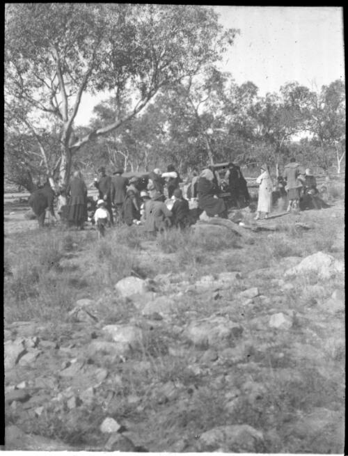 Group of unidentified people at a picnic? [transparency] : lantern slide used by Rev. F.H. Paterson, north South Australia / [John Flynn?]