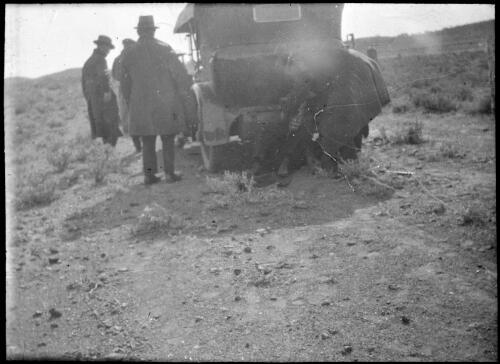 Group of unidentified men fixing a car [transparency] : lantern slide used by Rev. F.H. Paterson, north South Australia / [John Flynn?]