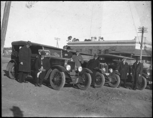 Men wearing hats and overcoats standing near three cars [transparency] : a deputation lantern slide of the AIM [Australian Inland Mission] Head Office, 1926-1940 / [John Flynn?]