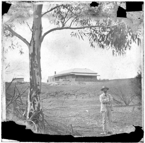 Unidentified homestead, gum tree and unidentified man in foreground, South Australia [transparency] : lantern slide used by Rev. F.H. Paterson, north South Australia / [John Flynn?]