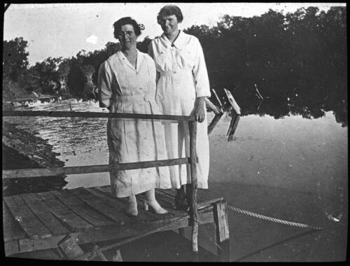 Two nurses standing on a jetty [transparency] : a deputation slide of the AIM [Australian Inland Mission] Head Office, 1926-1940 / [John Flynn?]