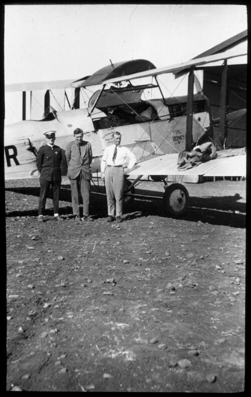 Qantas pilot, Captain Evans with Dr. George Simpson (centre) and an ambulance officer from the Queensland Ambulance Transport Brigade standing in front De Havilland biplane "Hermes" on 2 August 1927, during preparations for a trial medical flight between Cloncurry and Mount Isa by what was to become the Flying Doctor Service [transparency]