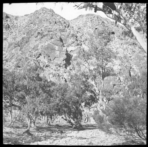 Unidentified rocky mountain with trees in foreground [transparency] : lantern slide used by Rev. F.H. Paterson, north South Australia / [John Flynn?]
