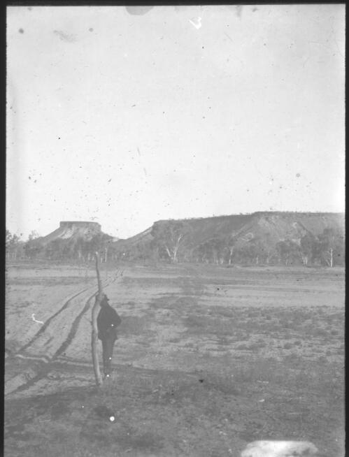 Unidentified man standing next to dirt road with mountain range in background, South Australia [transparency] : scene of mid-north South Australia used by Rev. F.H. Patterson on Stuart Patrol 1930+