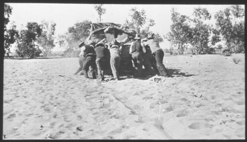Road to Granites, eight unidentified men pushing a car over sand, South Australia [transparency] : scene of mid-north South Australia used by Rev. F.H. Patterson on Stuart Patrol 1930+