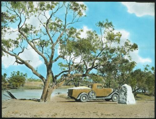 A yellow truck near a rock, 26 miles from Innamincka [transparency] : a lantern slide used in lectures on all Australian Inland Mission activities, 1940- / [John Flynn?]