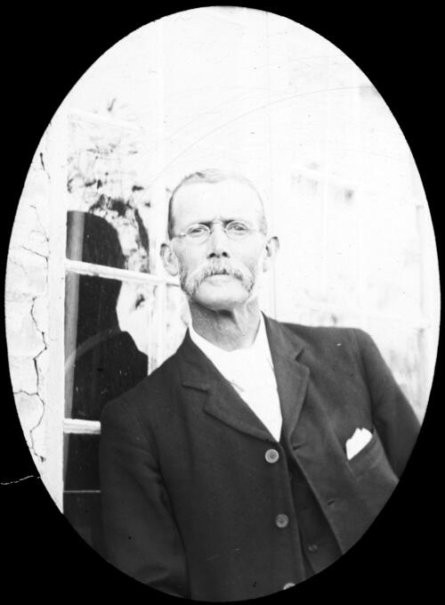 Portrait of an unidentified man standing leaning against a window sill [transparency] : lantern slide used by Rev. F.H. Paterson, north South Australia / [John Flynn?]