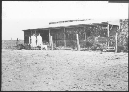 Two women standing beside a building at Birdsville [transparency] : a lantern slide used in lectures on all Australian Inland Mission activities, 1940- / [John Flynn?]