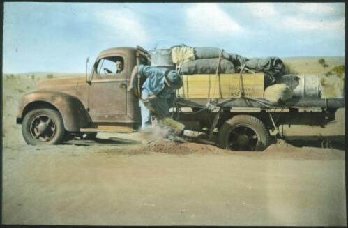 Car bogged on dirt track, unidentified man trying to move the car [transparency] : a lantern slide used in lectures on all Australian Inland Mission activities, 1940- / [John Flynn?]
