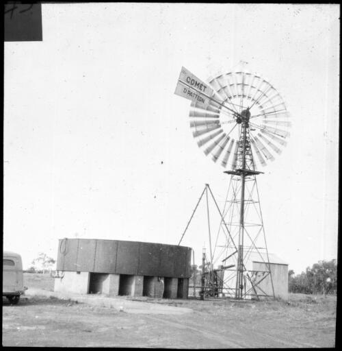 Windmill and water tank on raised platform, Birdsville [transparency] : a lantern slide used in lectures on all Australian Inland Mission activities, 1940- / [John Flynn?]