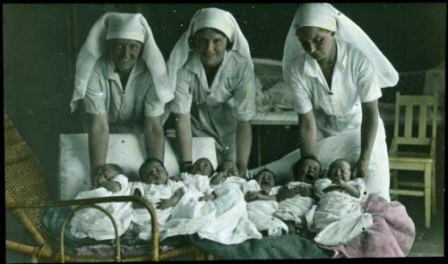 Three unidentified nurses with seven newborn babies [transparency] : a lantern slide used in lectures on all Australian Inland Mission activities, 1940- / [John Flynn?]