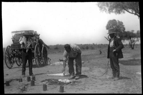Three unidentified men making johnny cakes on a camp fire [transparency] : part of a mixed selection of lantern slides and negatives from John Flynn's teaching days in Gippsland, and early AIM [Australian Inland Mission] activities / John Flynn