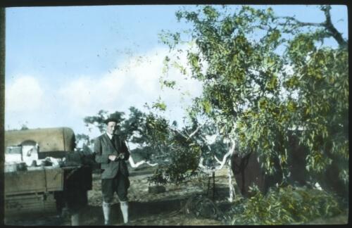 Unidentified man standing next to utility truck at campsite [transparency] / [John Flynn?]