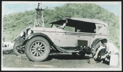 Unidentified man setting up communications equipment next to car [transparency] / [John Flynn?]