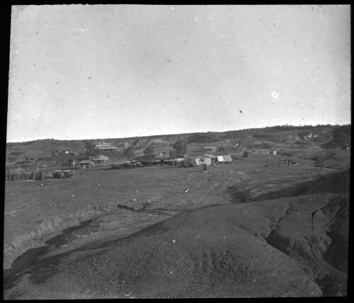 Unidentified town surrounded by eroded hills [transparency] / [John Flynn?]