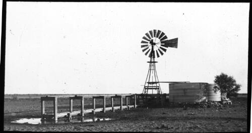 Windmill and water tank [transparency] : part of scenes of the Northern Territory and North Western Australia / [John Flynn?]