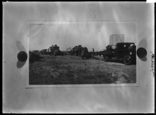 Unidentified men and trucks on dirt road [picture] / [John Flynn?]