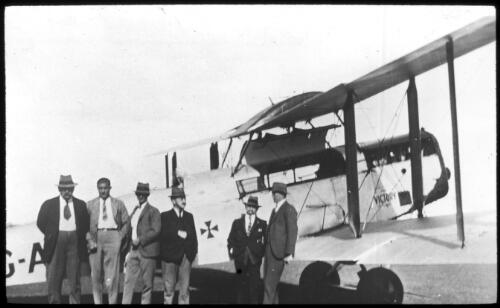 Group of men standing in front of the aeroplane "Victory" [transparency] / [John Flynn?]