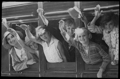 Children's camp [girls leaning out of train carriage windows] [transparency] : part of a lantern slide lecture collection / [John Flynn?]