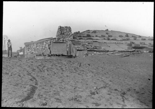Sanded house [made from rock and corrugated iron] [transparency] : part of a lantern slide lecture collection / [John Flynn?]