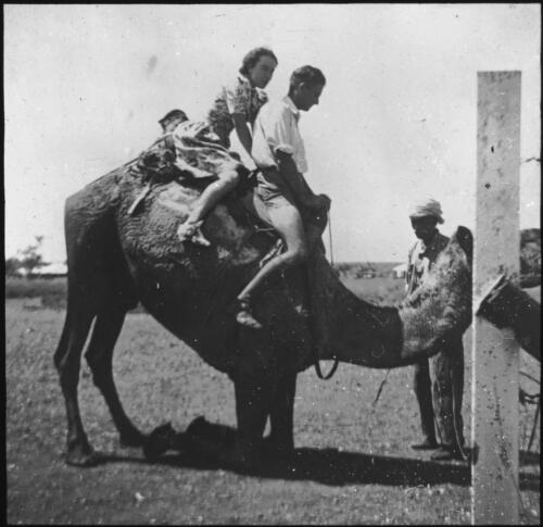 First camel ride [unidentified man and a woman sitting on camel] [transparency] : general Australian Inland Mission scenes / [John Flynn?]