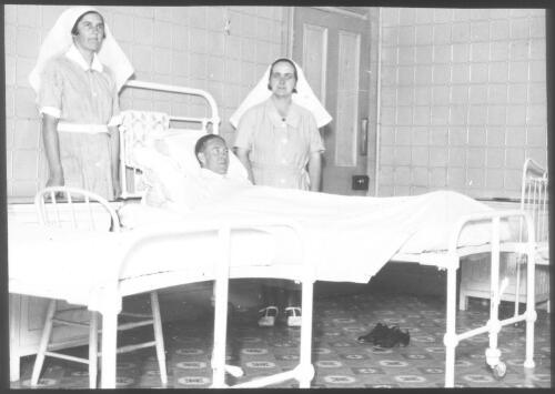 Hospital ward at Oodnadatta with two unidentified nurses and a patient [transparency] : scenes of Tennant Creek and the Northern Territory, Beltana, Oodnadatta, and other general scenes / [John Flynn?]