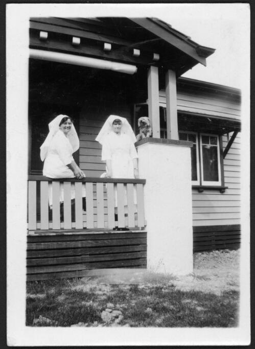Portrait of Sisters King and Gray of the Victoria River Downs Nursing Home with a dog on the verandah of an unidentified building in Melbourne, Victoria [picture] / [John Flynn?]
