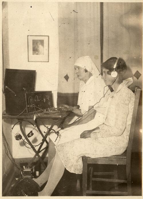 Sister D. Burchill in uniform with Sister I. Currey using the wireless at Innamincka, September 1931 [picture] / [John Flynn?]
