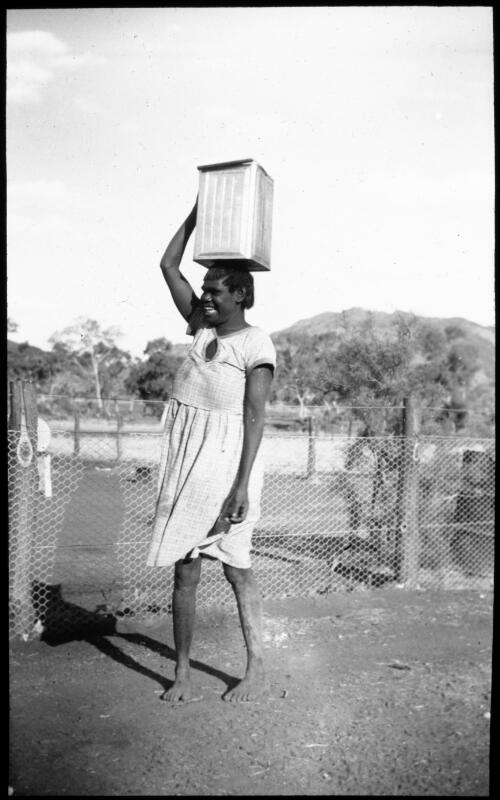 Woman carrying a container on her head at Ernabella Mission, South Australia, 1949 [transparency] / C. Duguid