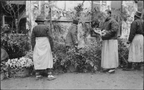 [Flower sellers with mostly greenery and one basket of flowers all against the wall of the building, China, ca. 1930] [picture] / Stanley O. Gregory