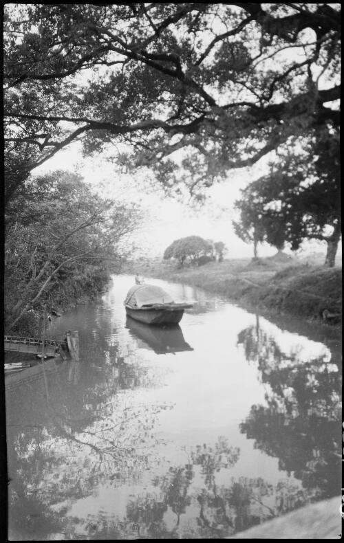 [Sampan on small canal with figure standing on stern with a pole, China, ca. 1930] [picture] / Stanley O. Gregory