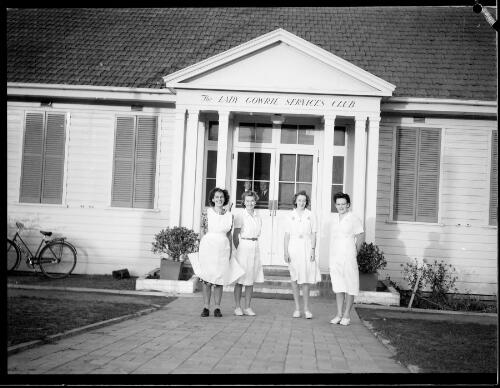 Four women in white uniforms standing outside the Lady Gowrie Services Club, Manuka, Canberra, ca. 1940s [picture] / L.J. Dwyer