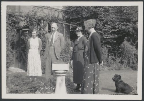 Group portrait of Miss A.M. Deane [?], second from right, with Henry J. Deane and his wife and daughter standing around a sundial, 1937 [picture]