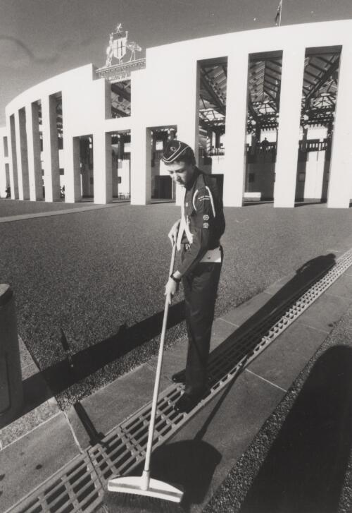 A Boy's Brigade member sweeps the forecourt  of the new Parliament House, Canberra, 1988 [picture] / Andrew Campbell