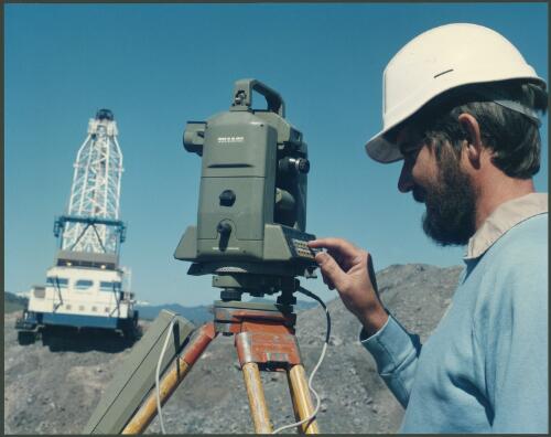Surveyor with dragline in background at Drayton coal mine near Muswellbrook, New South Wales, 1985 [picture] / Wolfgang Sievers