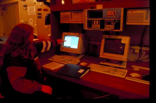 Biologist Kerry Steinberger demonstrates how temperature and depth data is retrieved and graphed on a central computer providing information on the Southern Ocean by latitude, Aurora Australis, Antarctic Ocean,  27 September 1997 [transparency] / Felicity Jenkins
