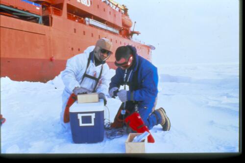 Veterinarians Dr Michael Lynch and Dr Damian Higgins prepare an ECG unit encased in esky and hot water bottles used to monitor seals during capture, Aurora Australis, Antarctic Ocean, 6 October 1997 [transparency] / Felicity Jenkins