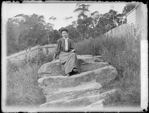 Winifred Cazneaux sitting on a rock in a backyard, North Sydney, ca. 1910 [picture] / Harold Cazneux