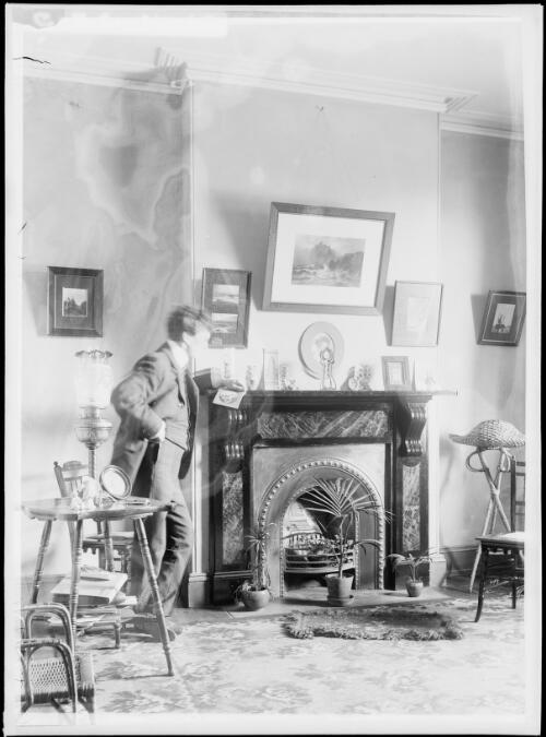Harold Cazneaux standing at living room fireplace, North Sydney, ca. 1910 [picture]