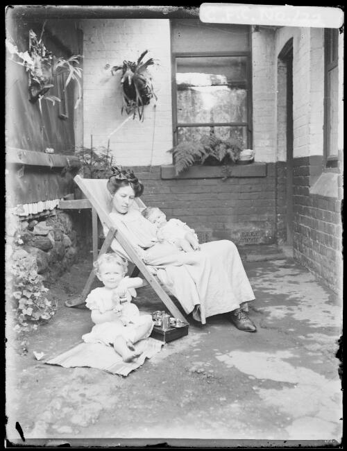 Winifred in deck chair with baby Jean and Rainbow at Riley Street, North Sydney, 1910 [picture] / Harold Cazneaux