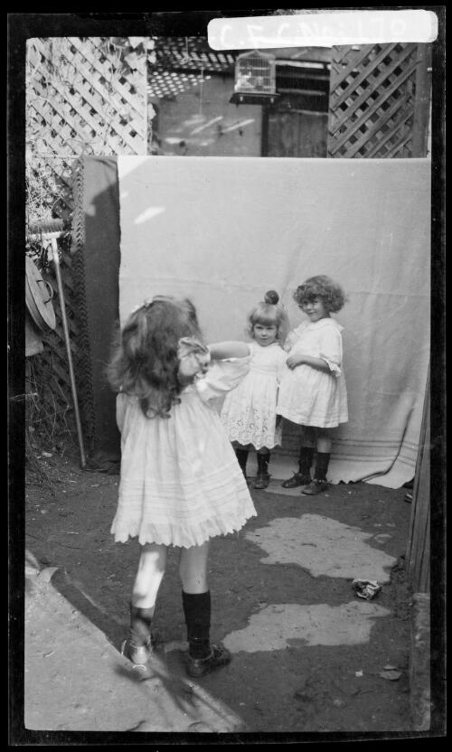 Beryl, Rainbow and Jean Cazneaux playing outside, Beryl with a ball on her head, Riley Street, North Sydney, 1913 [picture] / Harold Cazneaux
