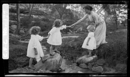 Winifred Cazneaux crossing a creek with Rainbow, Jean and Beryl, 1914? [picture] / Harold Cazneaux