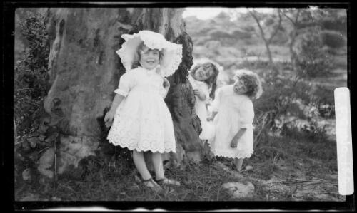 Beryl leaning against a tree while Rainbow and Jean look out from behind, 1914? [picture] / Harold Cazneaux
