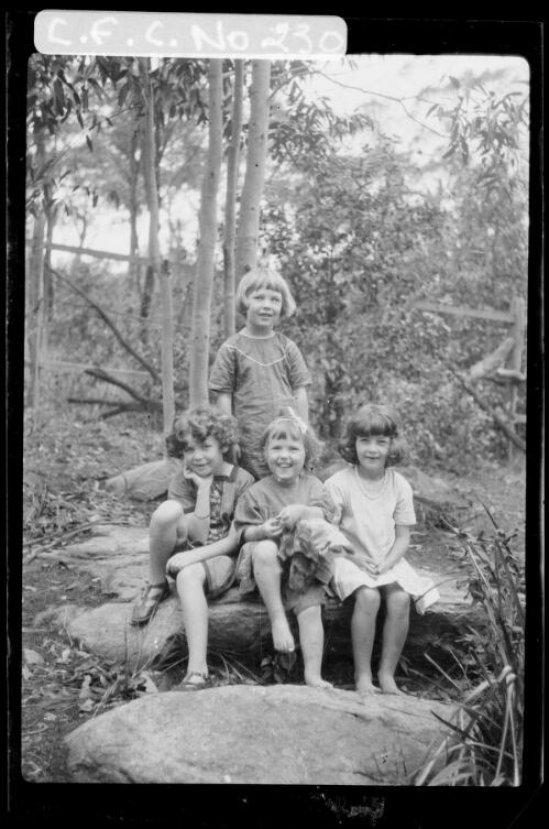 Beryl standing, Rainbow, Carmen and Jean sitting on a log, Ambleside, Roseville, New South Wales, 1916 [picture] / Harold Cazneaux
