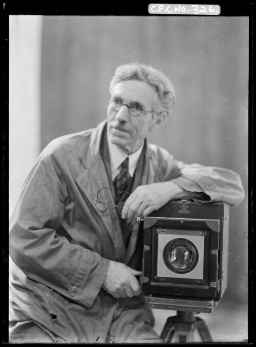 Harold Cazneaux leaning on a camera looking to one side, 1930s? [picture] / Harold Cazneaux