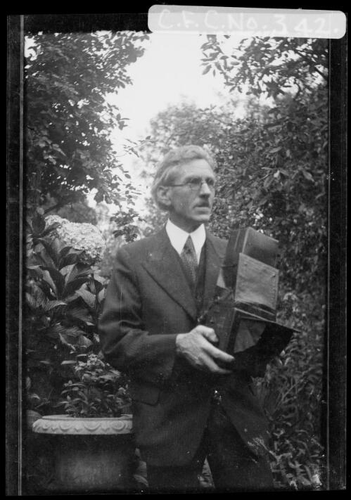 Harold Cazneaux holding a camera in the garden at Ambleside, Roseville, New South Wales, 1940? [picture] / Harold Cazneaux