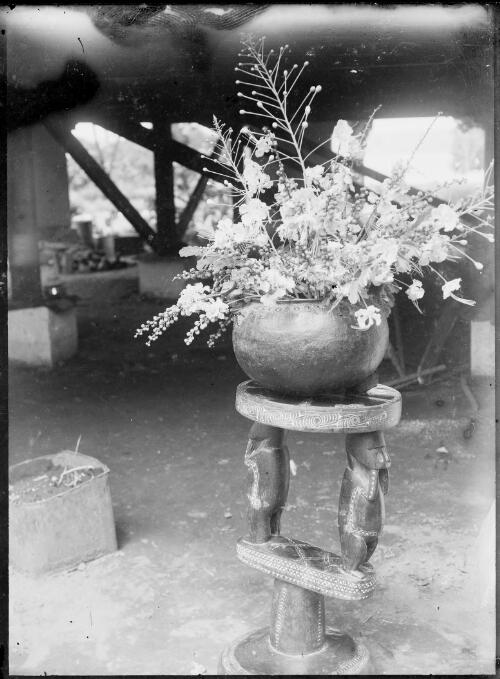 New Guinea flowers in a round bowl on a Trobriand Island stool,  Rabaul, New Guinea, ca. 1929 [picture] / Sarah Chinnery