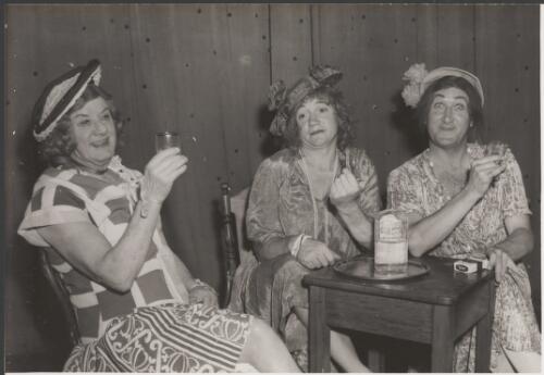 Jim Gerald, Keith Petersen and George Wallace Junior dressed as housewives at a table, ca. 1960 [picture] / produced by H. Williamson & Co., Sydney